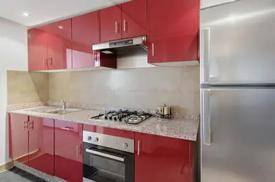 a kitchen with red cabinets and a stainless steel refrigerator at Modern apartment, swimming pool and sports in Marrakech