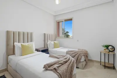 two beds in a white room with a window at Modern apartment, swimming pool and sports in Marrakech