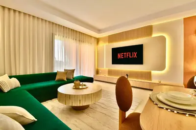 a living room with a green couch and a tv at Noria Residence - Premium 2BR Apartment with Pool View in Marrakech