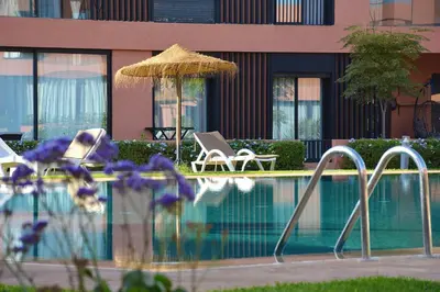 a swimming pool with two chairs and an umbrella at Noria Residence - Premium 2BR Apartment with Pool View in Marrakech