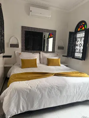 a bedroom with a large white bed with yellow pillows at Ryad Lalla khadija in Marrakech