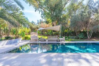 a pool with two chairs and a gazebo at Luxurious villa Marrakech La Palmeraie in Marrakech