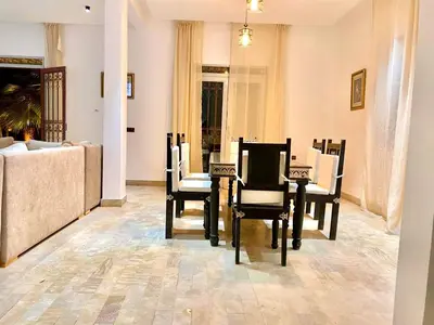 a dining room with chairs and a table and a couch at Charmante villa avec piscine privée et jardin in Marrakech