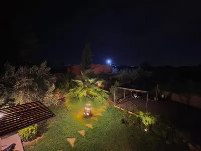 a night view of a garden with palm trees and lights at Charmante villa avec piscine privée et jardin in Marrakech