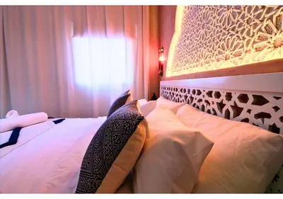 a bedroom with a bed with white pillows and a window at Luxury Riad Marrakech - 3BR - Rooftop - Jacuzzi in Marrakech