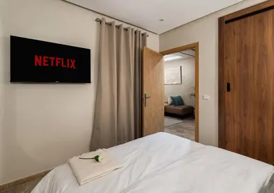 a bedroom with a bed with a netflix sign on the wall at Appartement Chic & Neuf à Guéliz - Terrasse et Parking in Marrakech