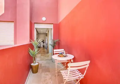 a room with a red wall with a table and chairs at Appartement Chic & Neuf à Guéliz - Terrasse et Parking in Marrakech
