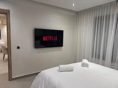 a bedroom with a bed with a television on the wall at Refined Apartment in Guéliz Laya Home Luxury in Marrakech