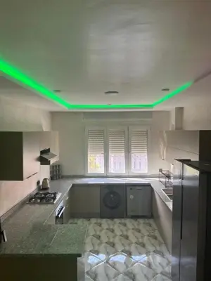 a kitchen with green lights on the ceiling at Appartement Abdessamad Hébergement réservé aux familles in El Gouassem