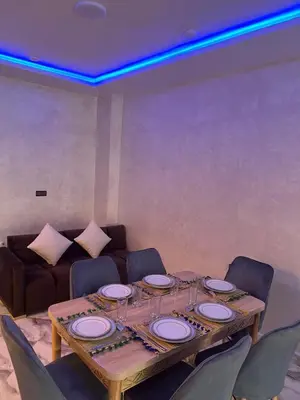 a dining room table with chairs and a couch at Appartement Abdessamad Hébergement réservé aux familles in El Gouassem