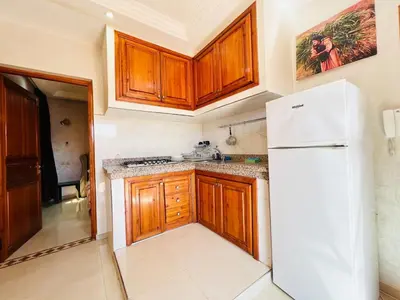 a kitchen with wooden cabinets and a white refrigerator at Cycas Family aparts 1 ch salon parking in Marrakech