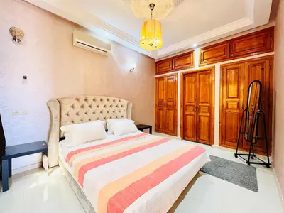 a bedroom with a bed with a colorful striped blanket at Cycas Family aparts 1 ch salon parking in Marrakech