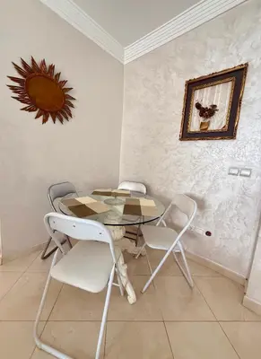 a dining room with a glass table and white chairs at Layla Apartment in Marrakech
