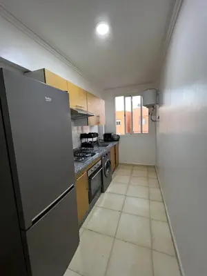 a kitchen with a refrigerator and a stove top oven at Appartement bien équipé avec piscine sur Marrakech in Marrakech