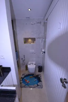 a bathroom with a toilet with a painting on the floor at Appartement Spacieux Idéal Séjours Longs in Marrakech