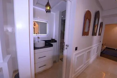 a white bathroom with a sink and a mirror at Appartement Spacieux Idéal Séjours Longs in Marrakech