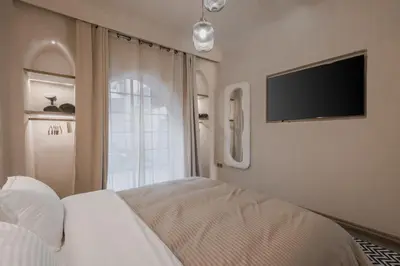 a bedroom with a bed and a flat screen tv at City Center 1 BED Apartments - Miramas - Pool and gym in Marrakech