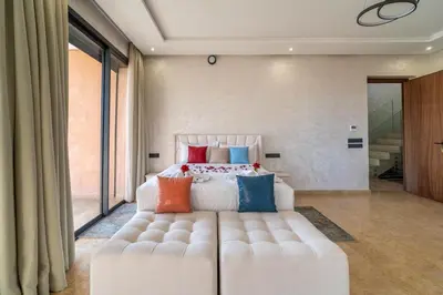 a bedroom with a large white bed with colorful pillows at Luxury Villa Hammam Piscine chauffeé sans Vis Avis in El Harkat