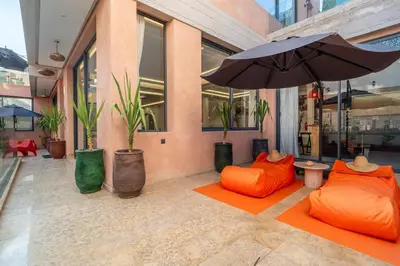 a building with two orange chairs and an umbrella at Luxury Villa Hammam Piscine chauffeé sans Vis Avis in El Harkat