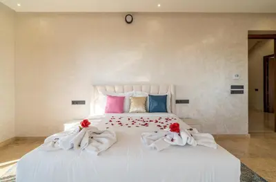 a bedroom with a white bed with red roses on it at Luxury Villa Hammam Piscine chauffeé sans Vis Avis in El Harkat