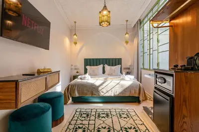 a bedroom with a bed and two blue chairs at Riad Janate BAHIA & Spa in Marrakech