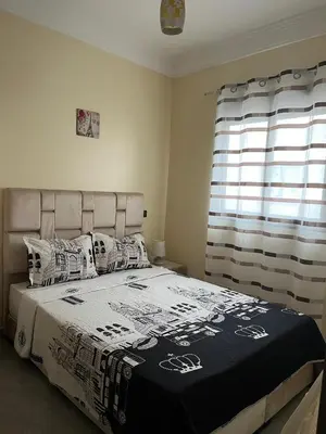 a bedroom with a large bed with pillows and a window at Appartement très bien meublé in Marrakech