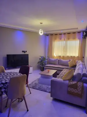 a living room with a couch and a tv at Nour Prestige Appartement Moderne Piscines Résidence Sécurisée in Marrakech