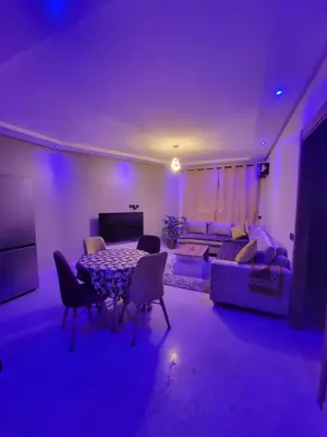 a living room with a table and a couch at Nour Prestige Appartement Moderne Piscines Résidence Sécurisée in Marrakech