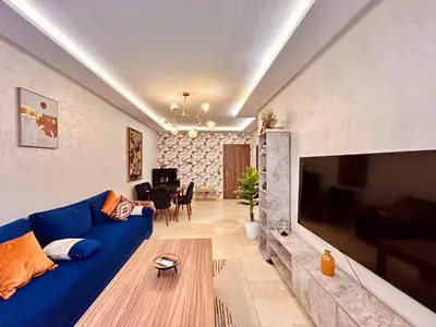 a living room with a blue couch and a large tv at Appartement Chic près M Avenue Piscine Balcon in Marrakech