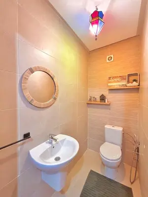 a bathroom with a sink and a toilet and a mirror at Appartement Chic près M Avenue Piscine Balcon in Marrakech