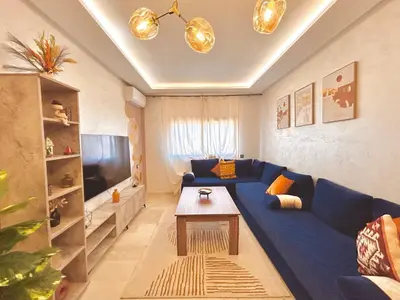 a living room with a blue couch and a table at Appartement Chic près M Avenue Piscine Balcon in Marrakech