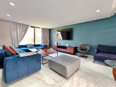 a living room with blue furniture and a tv at Duplexe Moderne 2 suites è Oliver Palm Resort in Marrakech