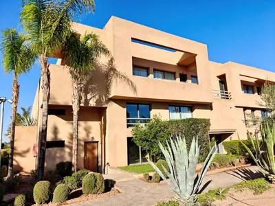 a building with palm trees in front of it at Duplexe Moderne 2 suites è Oliver Palm Resort in Marrakech