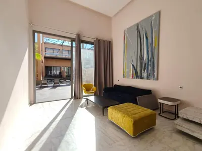 a living room with a couch and a yellow ottoman at Duplexe Moderne 3 suites à Oliver Palm Resort in Marrakech