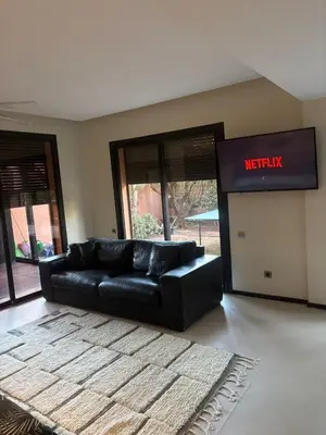 a black couch in a living room with a welcome sign at Appartement centre Marrakech avec piscine in Marrakech