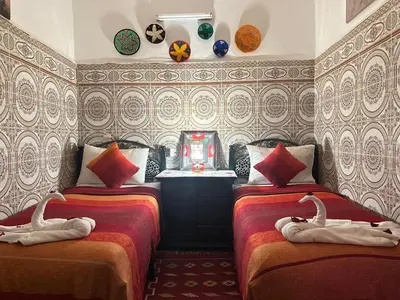 a bedroom with two beds with swans on them at Riad Dar Ceramic in Marrakech
