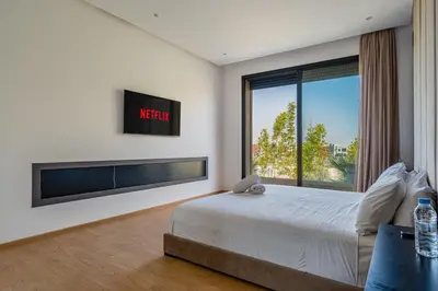 a bedroom with a large bed and a large window at Villa LUMA - Akenza Residence in El Rhechat