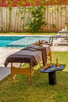 a table with a blanket on it next to a pool at Villa LUMA - Akenza Residence in El Rhechat