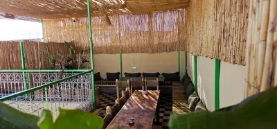 a room with chairs and a table and straw ceilings at Freedom Yan Hostel in Marrakech