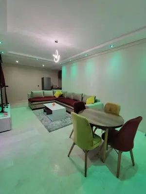 a living room with a couch and a table and chairs at Nour prestige Appartement Piscine free Parking in Marrakech
