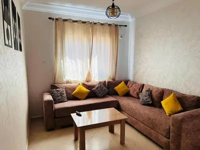 a living room with a brown couch with yellow pillows at Quiet &Bright Apartment in Marrakech