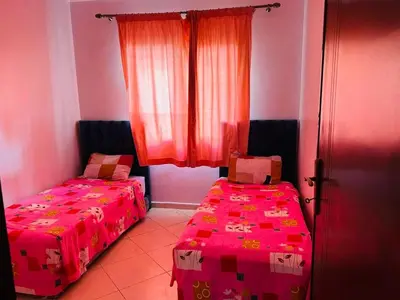 two beds in a room with pink walls and a window at Quiet &Bright Apartment in Marrakech