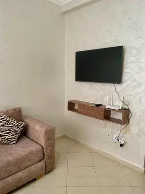 a living room with a couch and a television on a wall at Quiet &Bright Apartment in Marrakech