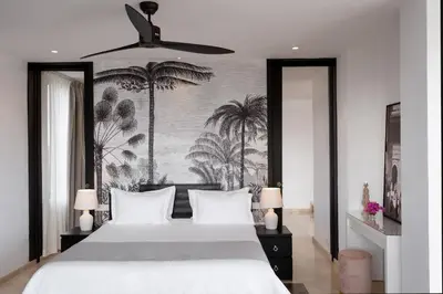a bedroom with a white bed with palm trees on the wall at Villa Montbel in Marrakech