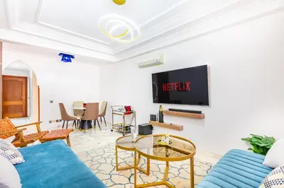 a living room with a blue couch and a tv at Perle Soft light and air conditioning in Marrakech