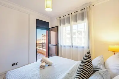a bedroom with a bed and a large window at Perle Soft light and air conditioning in Marrakech