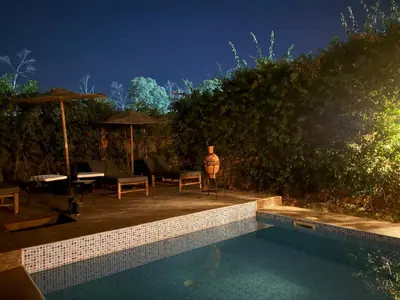 a swimming pool with chairs and umbrellas at night at Villa Bellisa in Marrakech