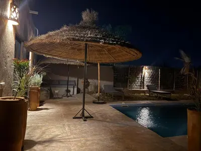 a large umbrella next to a swimming pool at night at Villa Lalla et Moulay in Marrakech
