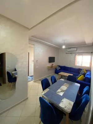 a living room with a table and a blue couch at Mhamid Appartement 3 chambres in Marrakech