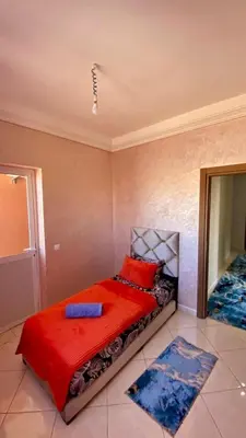 a bedroom with a bed with red pillows and a mirror at Mhamid Appartement 3 chambres in Marrakech